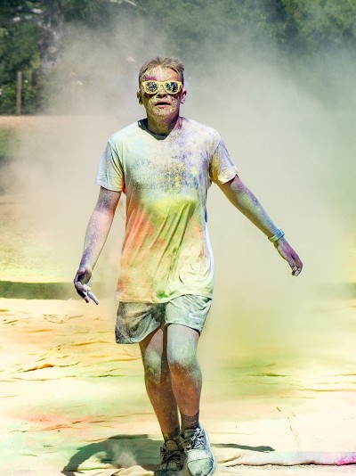 Boy crossing finish line covered in paint